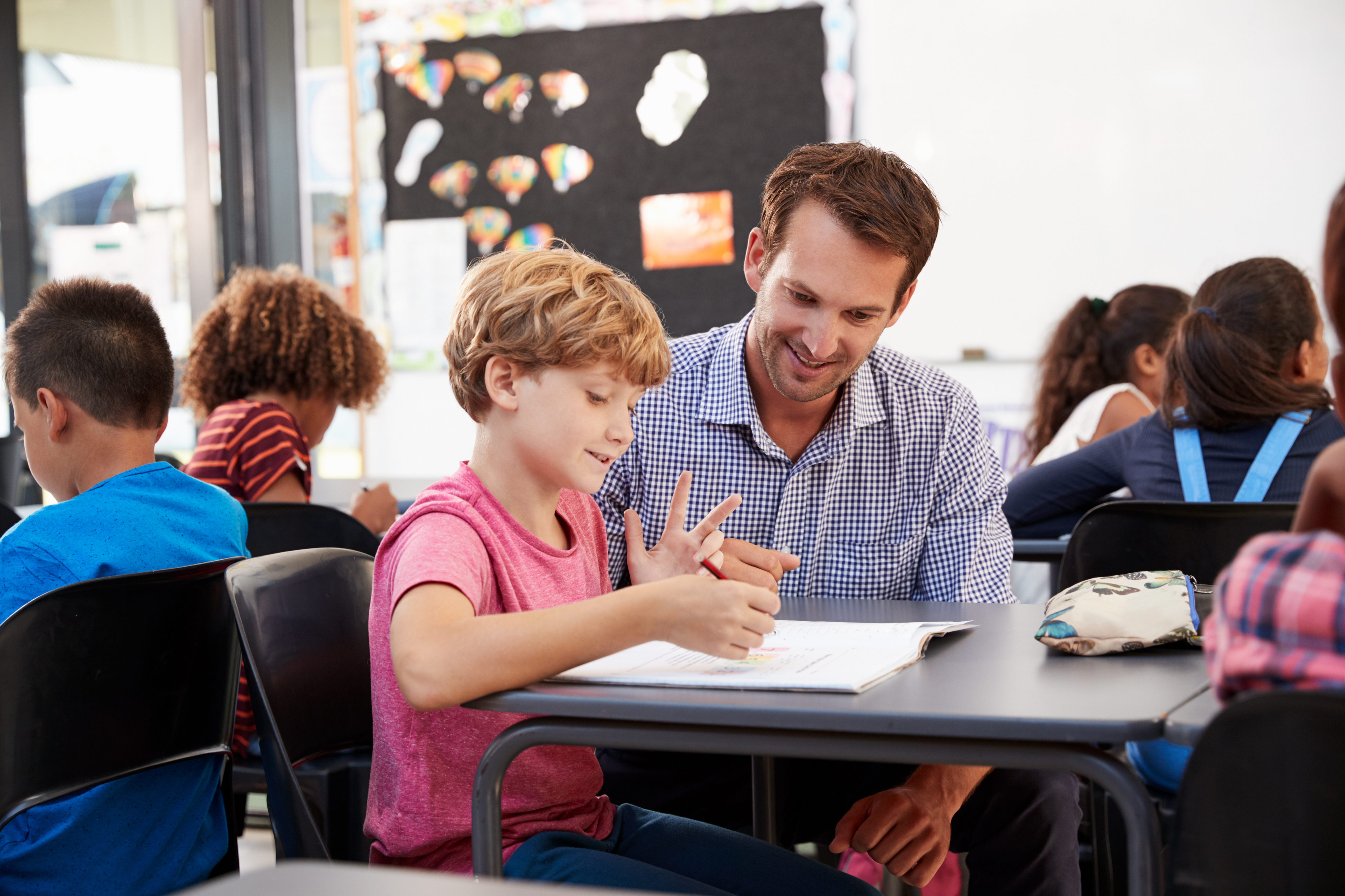 Begleitung unterstützt ein Kind beim Lernen im Klassenraum.