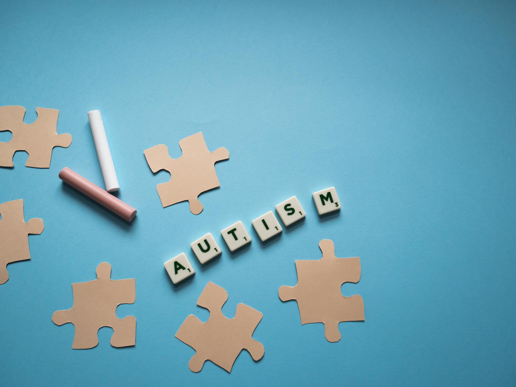 Puzzleteile und das Wort Autismus auf blauem Hintergrund.
