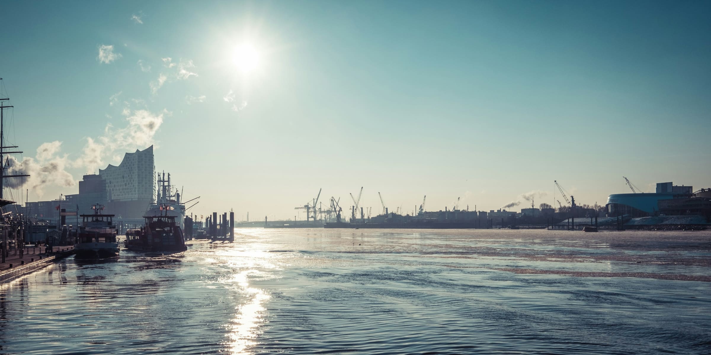 Blick über die Elbe mit Hafenkränen und Elbphilharmonie am Standort Hamburg-Nord.